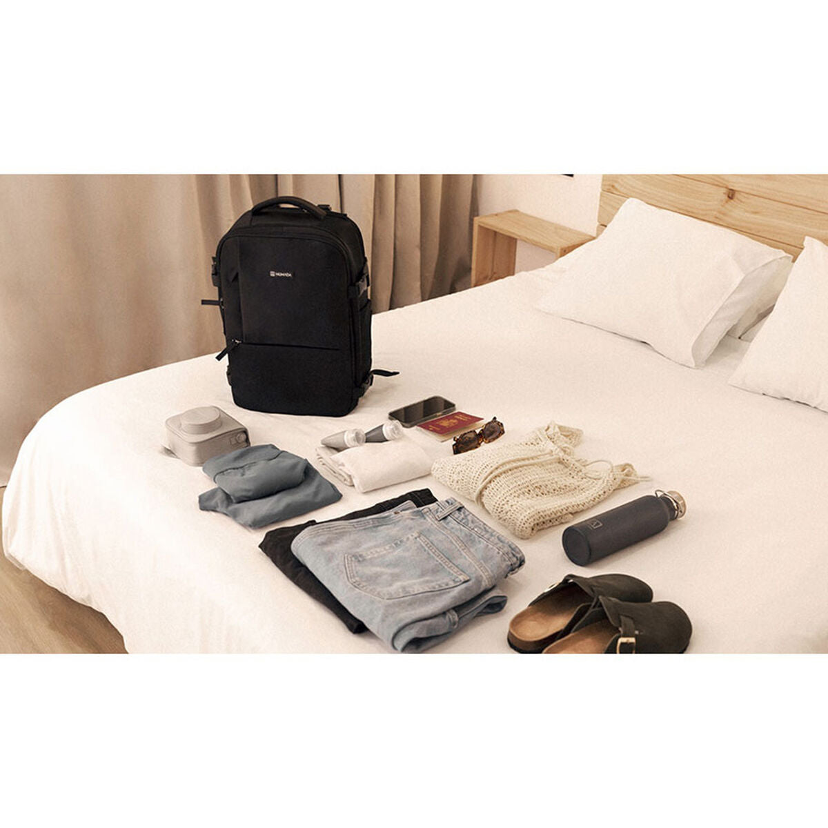 Numada Explorer B40 musta reppu sängyllä tavaroita vieressä