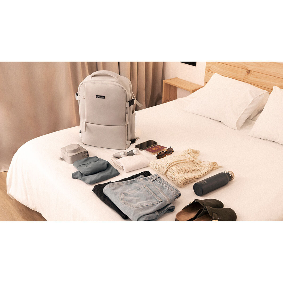 Numada b40 beige reppu sängyllä tavaroita vieressä
